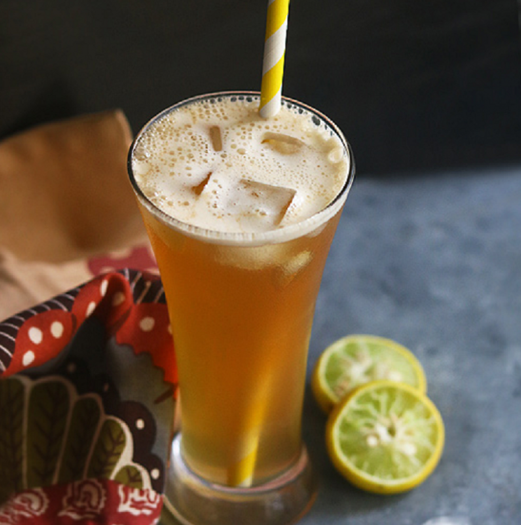 Organic Jaggery Powder Lemonade and ice cubes kept in a glass with a straw to drink from.