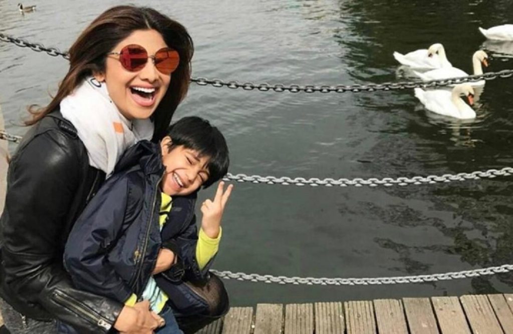Shilpa Shetty's Diet Plan For Weight Loss. Shilpa sitting and laughing with her son near a river bank.