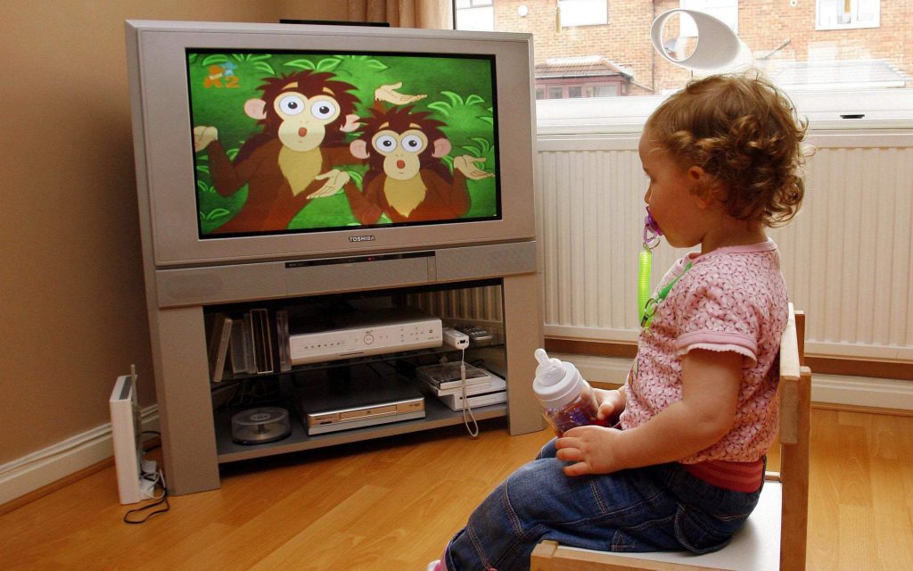 Steps To Screen-Free Mealtime. A girl enjoying the cartoon and holding the milk bottle.