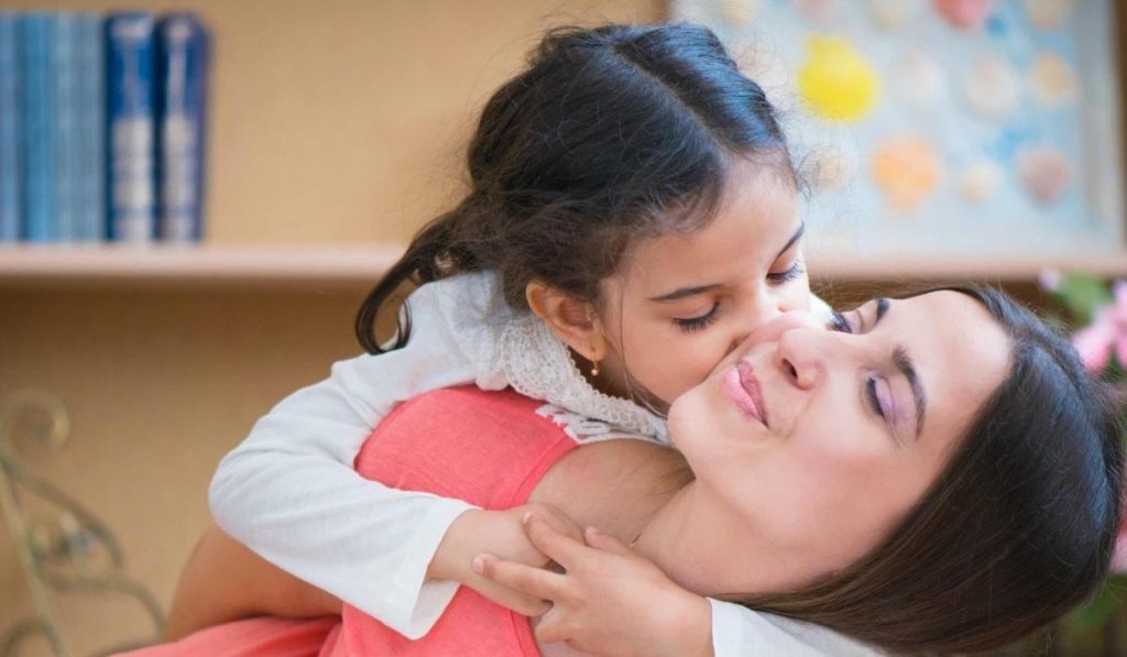 Positive parenting tips - A girl kissing her mother