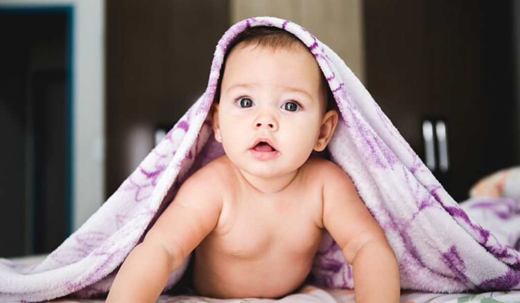 Child Care Tips Every Mom Should Follow During Monsoon. A child looking with a towel on his head.